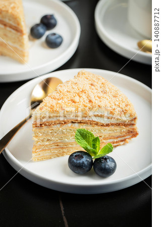 Medovik. Honey cake made from honey cakes with whipped sour cream, decorated with berries, pomegranate and flowers 140887712