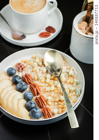 Oatmeal. Bowl of oatmeal porridge with blackberry, bananas and chia seeds on gray concrete old table background. Top view in flat lay style. Natural ingredients. Hot healthy breakfast and diet food Oatmeal. Bowl of oatmeal porridge with blackberry, bananas and chia seeds on gray concrete old table background. Top view in flat lay style. Natural ingredients. Hot healthy breakfast and diet food 140887713