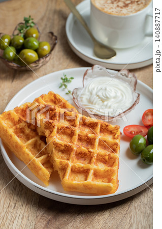 Crunchy waffle fries with sour cream dip served in a basket 140887717