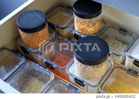 Clear plastic containers are filled with flour and grains. Well-organized kitchen cabinet drawer holds various dry goods Clear plastic containers are filled with flour and grains. Well-organized kitchen cabinet drawer holds various dry goods 140888422