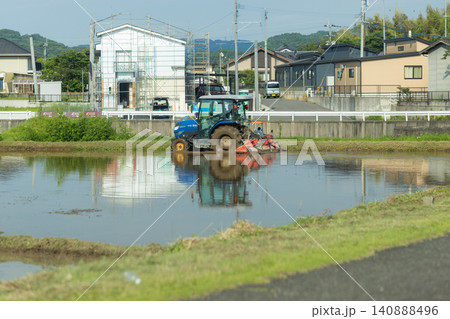 住宅街で行われる田植え前の作業 代かきを行う農家 住宅街で行われる田植え前の作業 代かきを行う農家 140888496