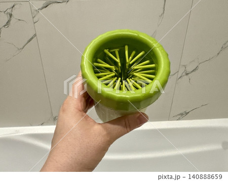 Close-up green paw washer cup for dog, Welsh Corgi cleaning paws after walk, pet hygiene and care concept at home Close-up green paw washer cup for dog, Welsh Corgi cleaning paws after walk, pet hygiene and care concept at home 140888659