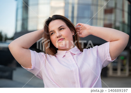 Young woman enjoying a relaxed moment outside a modern office building in an urban business district. Confidence freedom and relaxation for a balanced lifestyle 140889197