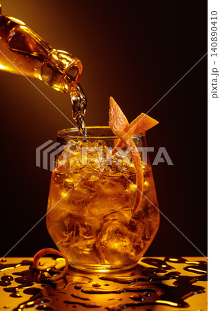 Old fashioned cocktail in a sweating glass on a wet black table. Old fashioned cocktail in a sweating glass on a wet black table. 140890410