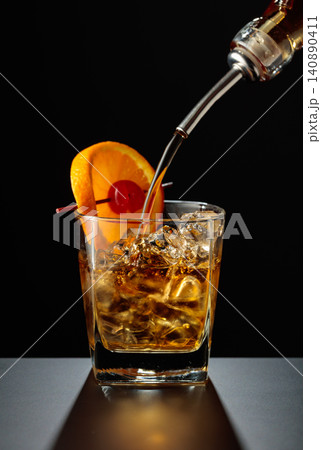 Old fashioned cocktail in a sweating glass on a black table. Old fashioned cocktail in a sweating glass on a black table. 140890411