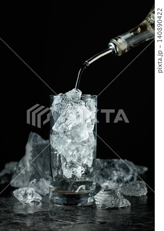 Strong liquor is poured into a glass with ice. Strong liquor is poured into a glass with ice. 140890422