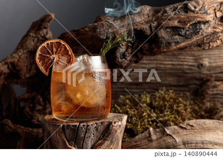 An old-fashioned cocktail over ice on an old wooden stump. An old-fashioned cocktail over ice on an old wooden stump. 140890444