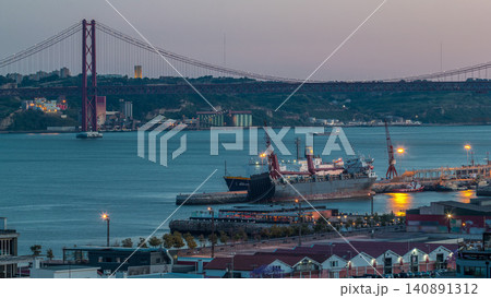 Skyline over Lisbon commercial port day to night timelapse, 25th April Bridge, containers on pier with freight cranes Skyline over Lisbon commercial port day to night timelapse, 25th April Bridge, containers on pier with freight cranes 140891312