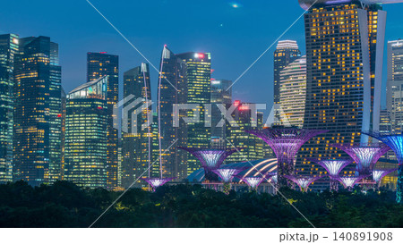 Skyscrapers behind Gardens by the bay with supertrees day to night timelapse after sunset Skyscrapers behind Gardens by the bay with supertrees day to night timelapse after sunset 140891908