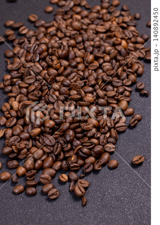Roasted coffee beans scattered on dark background forming a pile Roasted coffee beans scattered on dark background forming a pile 140892450