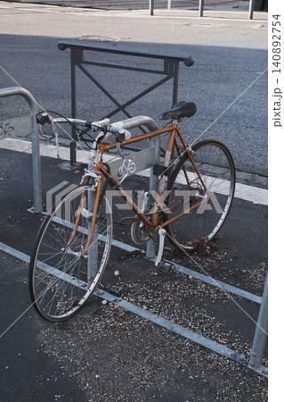 Rusty old bicycle locked in urban setting displays vandalism and weathered decay Rusty old bicycle locked in urban setting displays vandalism and weathered decay 140892754