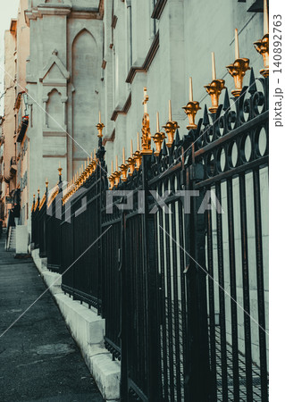 Elegant iron fencing with golden accents lining urban street near historic architecture Elegant iron fencing with golden accents lining urban street near historic architecture 140892763