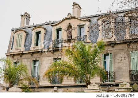Historic european stone building with rustic windows and palm trees in front Historic european stone building with rustic windows and palm trees in front 140892794
