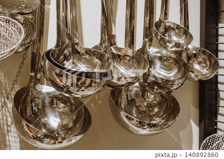 Shiny metal ladles hanging in kitchen display Shiny metal ladles hanging in kitchen display 140892860
