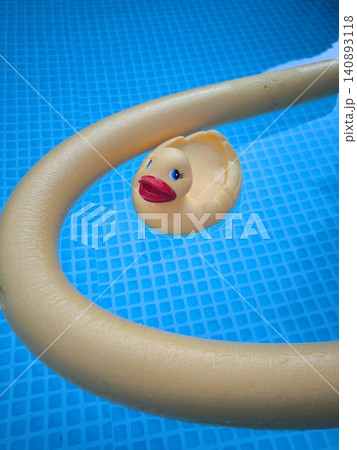 A yellow rubber duck floats in a pool with a flexible aqua noodle for water aerobics. A yellow rubber duck floats in a pool with a flexible aqua noodle for water aerobics. 140893118