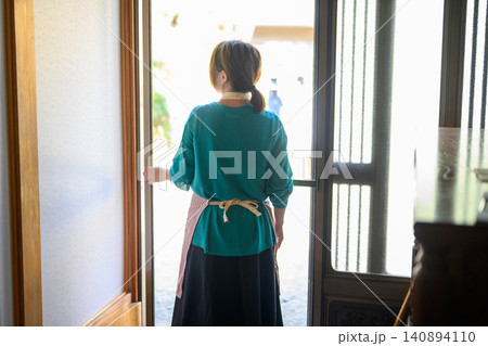 玄関のドアを開ける女性の後ろ姿 玄関のドアを開ける女性の後ろ姿 140894110