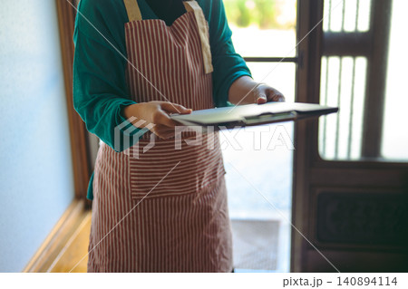 エプロン姿で回覧板を渡す女性 エプロン姿で回覧板を渡す女性 140894114