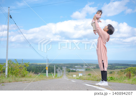 海の見える道で赤ちゃんを抱き上げる母親 海の見える道で赤ちゃんを抱き上げる母親 140894207