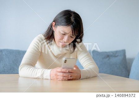 スマホを見て不安そうな女性 スマホを見て不安そうな女性 140894372
