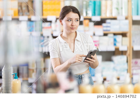 Woman standing in pharmacy with mobile phone Woman standing in pharmacy with mobile phone 140894702
