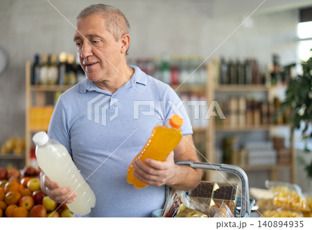 Mature man is choosing natural juice in grocery store Mature man is choosing natural juice in grocery store 140894935