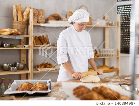 Adolescence girl baker works with rolling pin, rolls out and spreads out pieces of dough Adolescence girl baker works with rolling pin, rolls out and spreads out pieces of dough 140894987