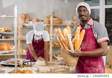 Adult man baker with basket of baguettes Adult man baker with basket of baguettes 140894993