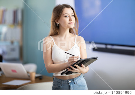 Young woman taking notes on tablet in office Young woman taking notes on tablet in office 140894996