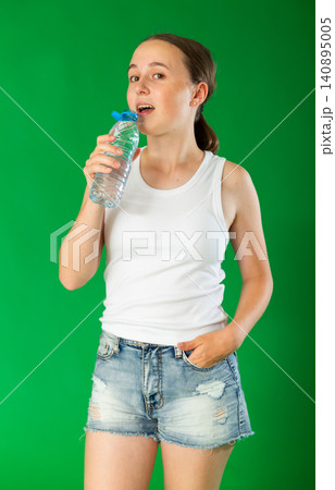 Teenage girl drinking water in front of green screen Teenage girl drinking water in front of green screen 140895005