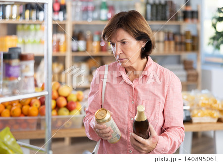 Choose alcohol in supermarket - woman chooses what beer to buy in alcohol section of store Choose alcohol in supermarket - woman chooses what beer to buy in alcohol section of store 140895061