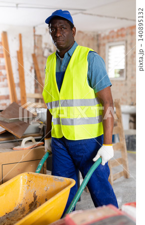 Man construction worker pushing cart in building site Man construction worker pushing cart in building site 140895132