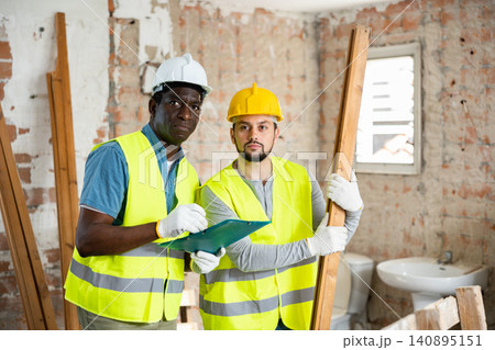 Two builders take notes, evaluating the work plan 140895151