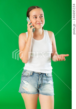 Teenage girl talking on mobile phone in front of green screen 140895154