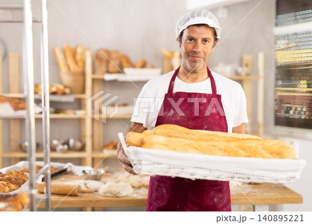 Adult male baker with basket of baguettes Adult male baker with basket of baguettes 140895221