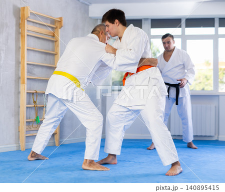 Young guy working on jiu-jitsu skills in training fight with male rival Young guy working on jiu-jitsu skills in training fight with male rival 140895415