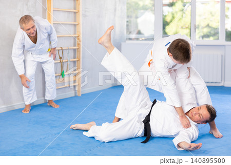 Focused guy practicing judo techniques in sparring with male opponent Focused guy practicing judo techniques in sparring with male opponent 140895500