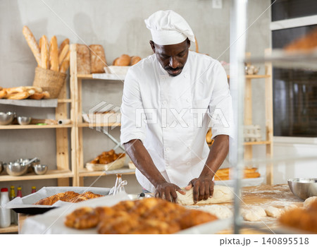 African American baker kneading dough in artisan bakery African American baker kneading dough in artisan bakery 140895518