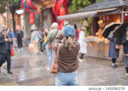Happy woman traveler travel in Chengdu city. Tourist sightseeing and taking photo in Kuan Zhai Alley or wide and narrow alleys, Famous Landmark for tourism attraction in Sichuan, China Happy woman traveler travel in Chengdu city. Tourist sightseeing and taking photo in Kuan Zhai Alley or wide and narrow alleys, Famous Landmark for tourism attraction in Sichuan, China 140896259