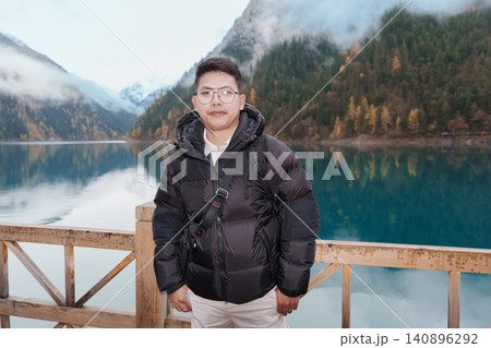 Happy man traveler travel in jiuzhaigou national park in Sichuan, China. Tourist sightseeing Long lake and snow mountain in Autumn season. Famous Landmark and Vacation near Chengdu, China Happy man traveler travel in jiuzhaigou national park in Sichuan, China. Tourist sightseeing Long lake and snow mountain in Autumn season. Famous Landmark and Vacation near Chengdu, China 140896292