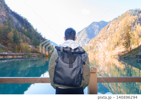 Happy man traveler travel in jiuzhaigou national park in Sichuan, China. Tourist sightseeing Panda lake and snow mountain in Autumn season. Famous Landmark and Vacation near Chengdu, China Happy man traveler travel in jiuzhaigou national park in Sichuan, China. Tourist sightseeing Panda lake and snow mountain in Autumn season. Famous Landmark and Vacation near Chengdu, China 140896294