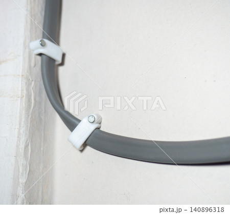 Fastening the wire to the wall. Ceiling mounting. Electric cord in the apartment. 220 volt. Fastening the wire to the wall. Ceiling mounting. Electric cord in the apartment. 220 volt. 140896318