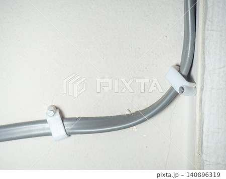 Fastening the wire to the wall. Ceiling mounting. Electric cord in the apartment. 220 volt. 140896319