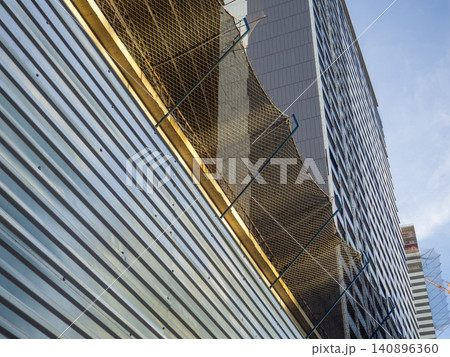 Glass facade of a house under construction with open windows. Construction safety net. Geometry in architecture. Glass facade of a house under construction with open windows. Construction safety net. Geometry in architecture. 140896360