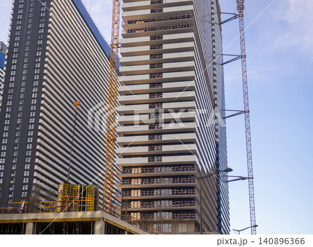 Glass facade of a house under construction with open windows. Windows opening outwards. Geometry in architecture. Glass facade of a house under construction with open windows. Windows opening outwards. Geometry in architecture. 140896366