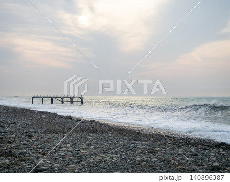 Destroyed pier under the waves. Bad weather at sea. Beautiful seashore with old architecture Destroyed pier under the waves. Bad weather at sea. Beautiful seashore with old architecture 140896387