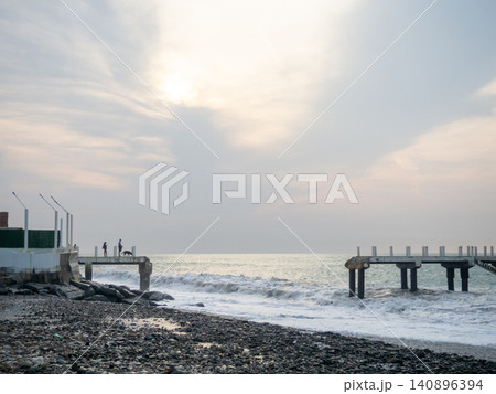 Destroyed pier under the waves. Bad weather at sea. Beautiful seashore with old architecture. 140896394