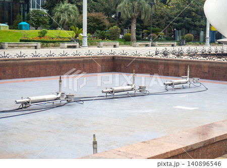 Empty fountain in a city park. Dehumidification. Cleaning the fountain with a hose. The device of the fountain. Pipes for water supply. Water hoses. Modern technologie Empty fountain in a city park. Dehumidification. Cleaning the fountain with a hose. The device of the fountain. Pipes for water supply. Water hoses. Modern technologie 140896546