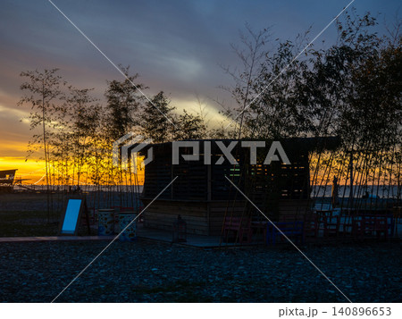 Restaurant on the seashore at sunset. sea coastal landscape. Restaurant at the resort. Thatched hut surrounded by bamboo Restaurant on the seashore at sunset. sea coastal landscape. Restaurant at the resort. Thatched hut surrounded by bamboo 140896653
