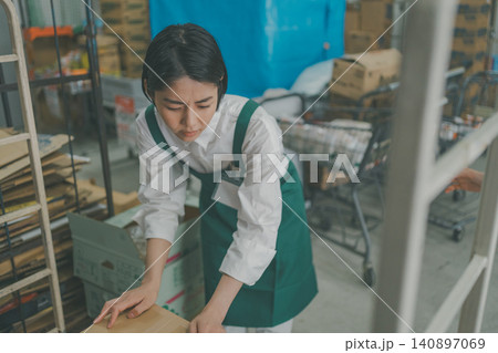 スーパーのバックヤードで体調不良に耐えながら作業する女性スタッフ スーパーのバックヤードで体調不良に耐えながら作業する女性スタッフ 140897069