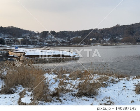 Winter sunset over snowy Korean lake with traditional pavilion and reeds, South Korea Winter sunset over snowy Korean lake with traditional pavilion and reeds, South Korea 140897145